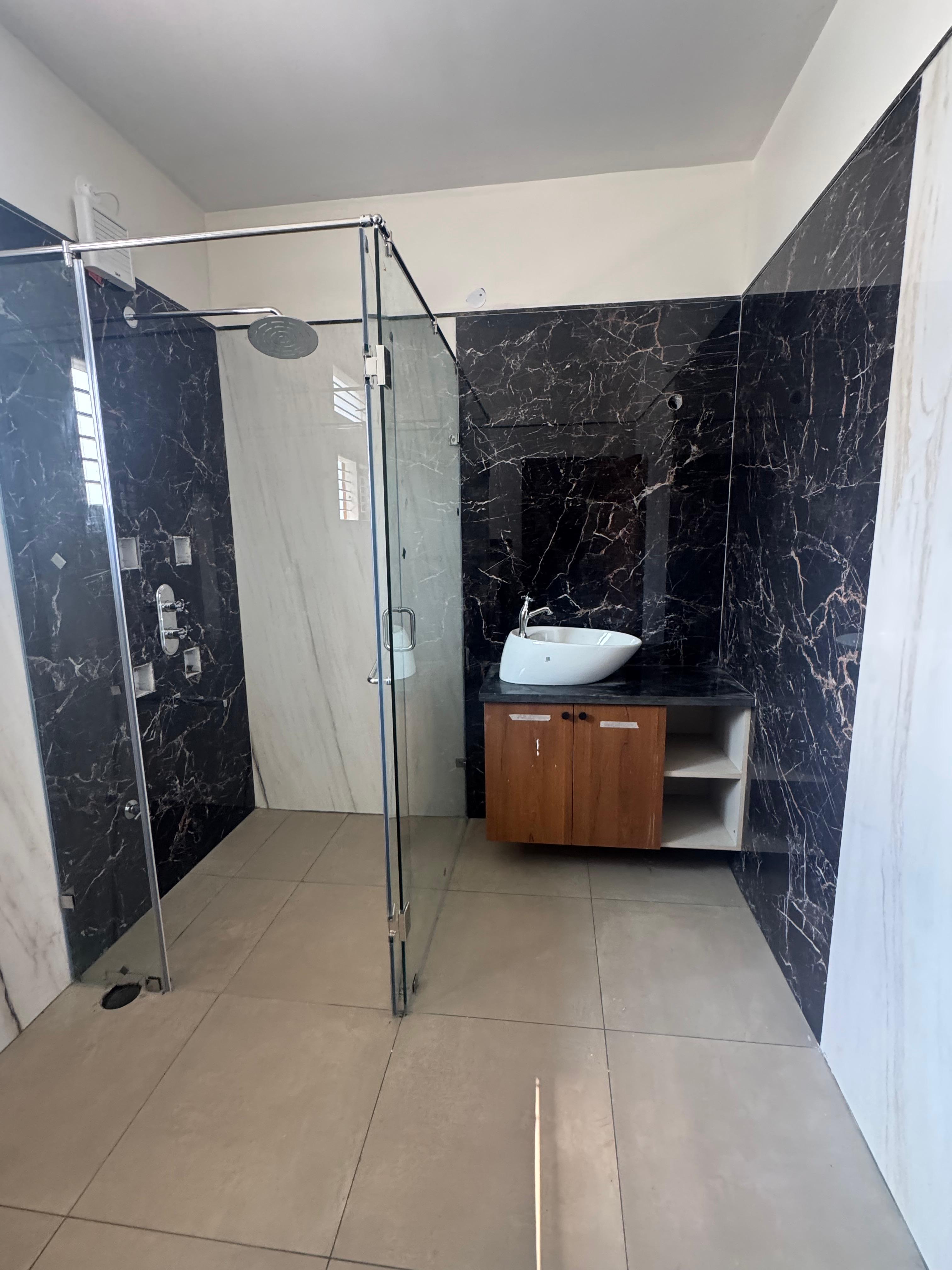 Bathroom vanity and glass shower partition with black marble tiles