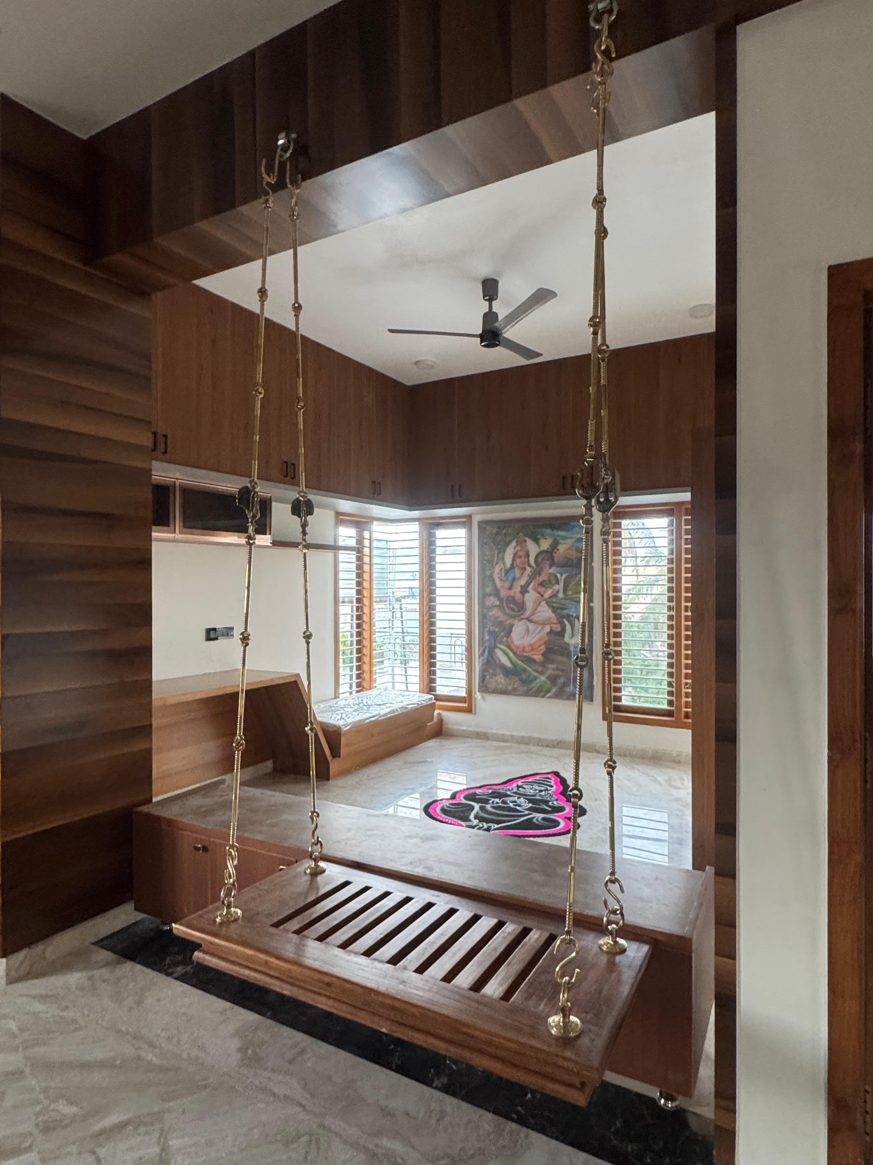 Pooja and living area with wooden swing and wall paneling